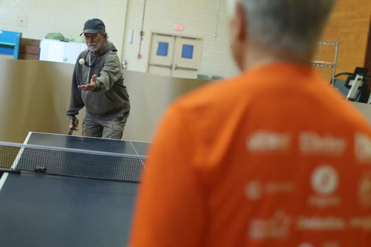 Elderly man playing ping pong in a healthcare setting, illustrating the importance of providers using best practices to address the mental health of elderly patients.
