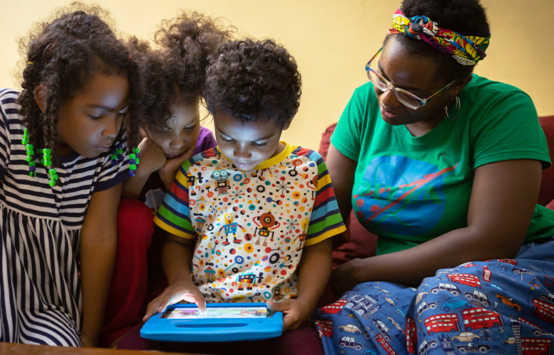 A photo of parent and children using tablet