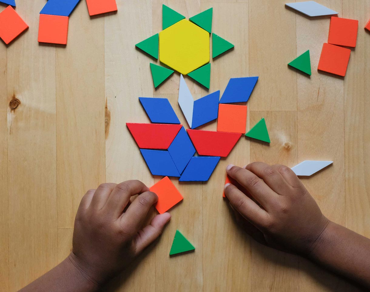Child’s hands arranging pattern blocks to make a flower.