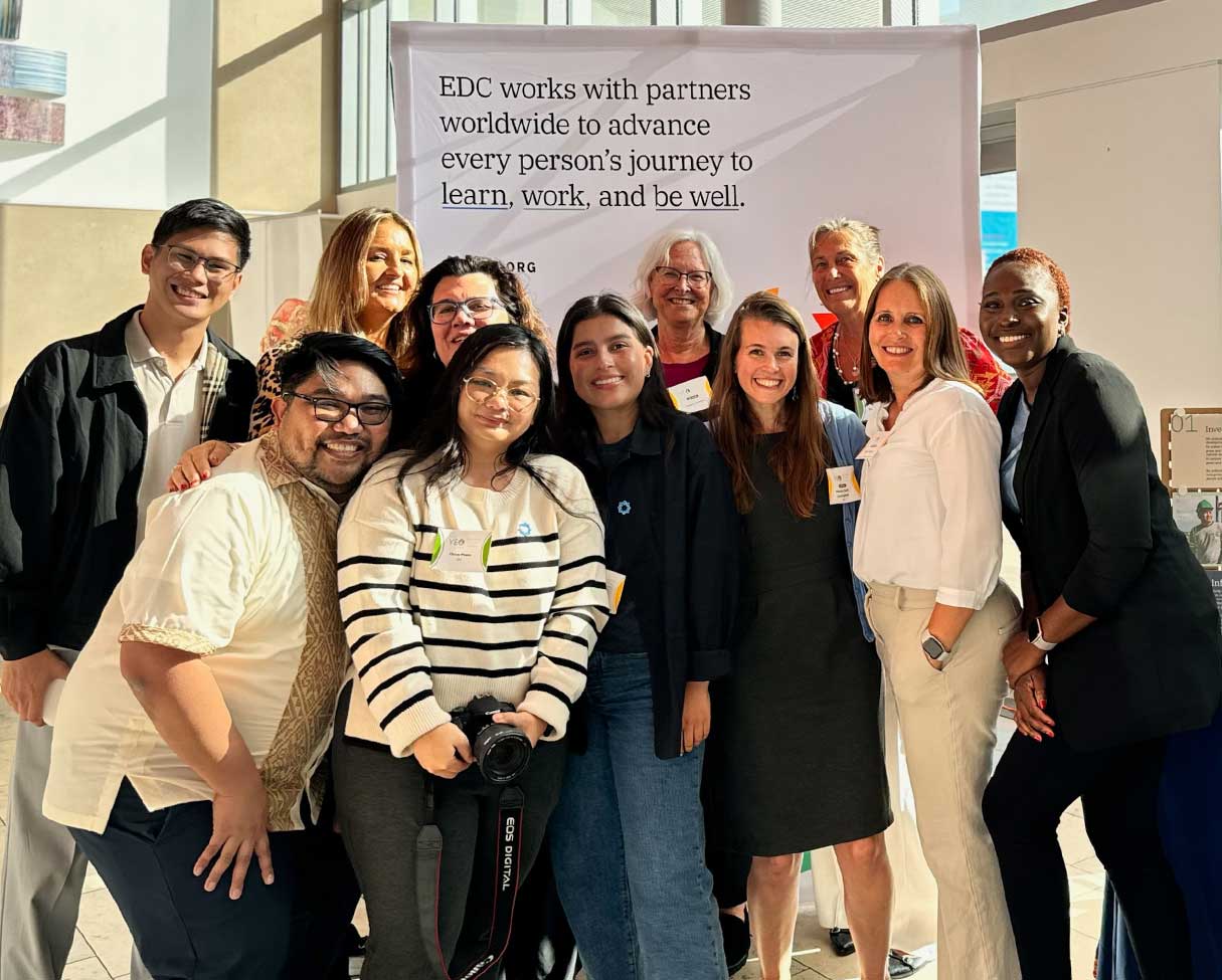 EDC team members standing together and smiling at the camera in front of EDC mission statement.