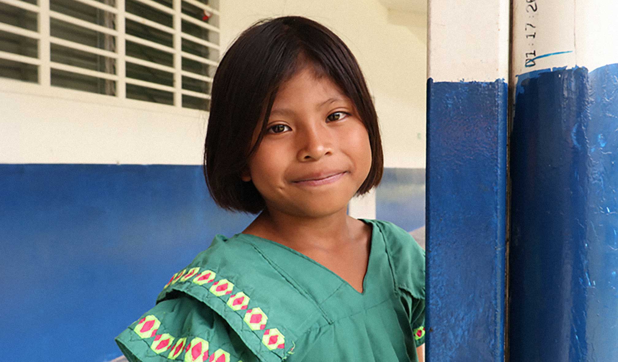 Young girl in a green dress smiling at the camera.