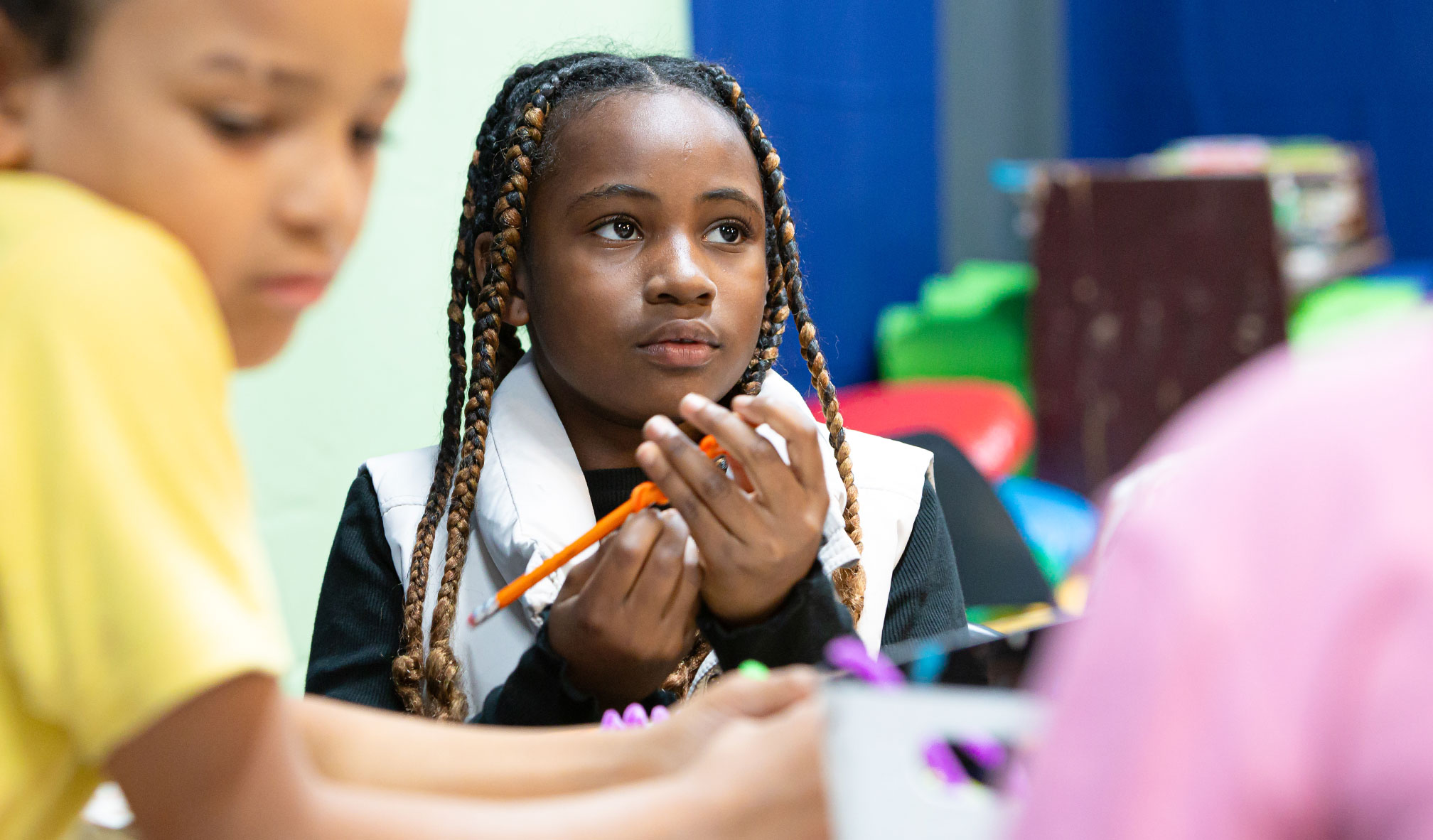 Primary school student facing the camera, holding a pencil.