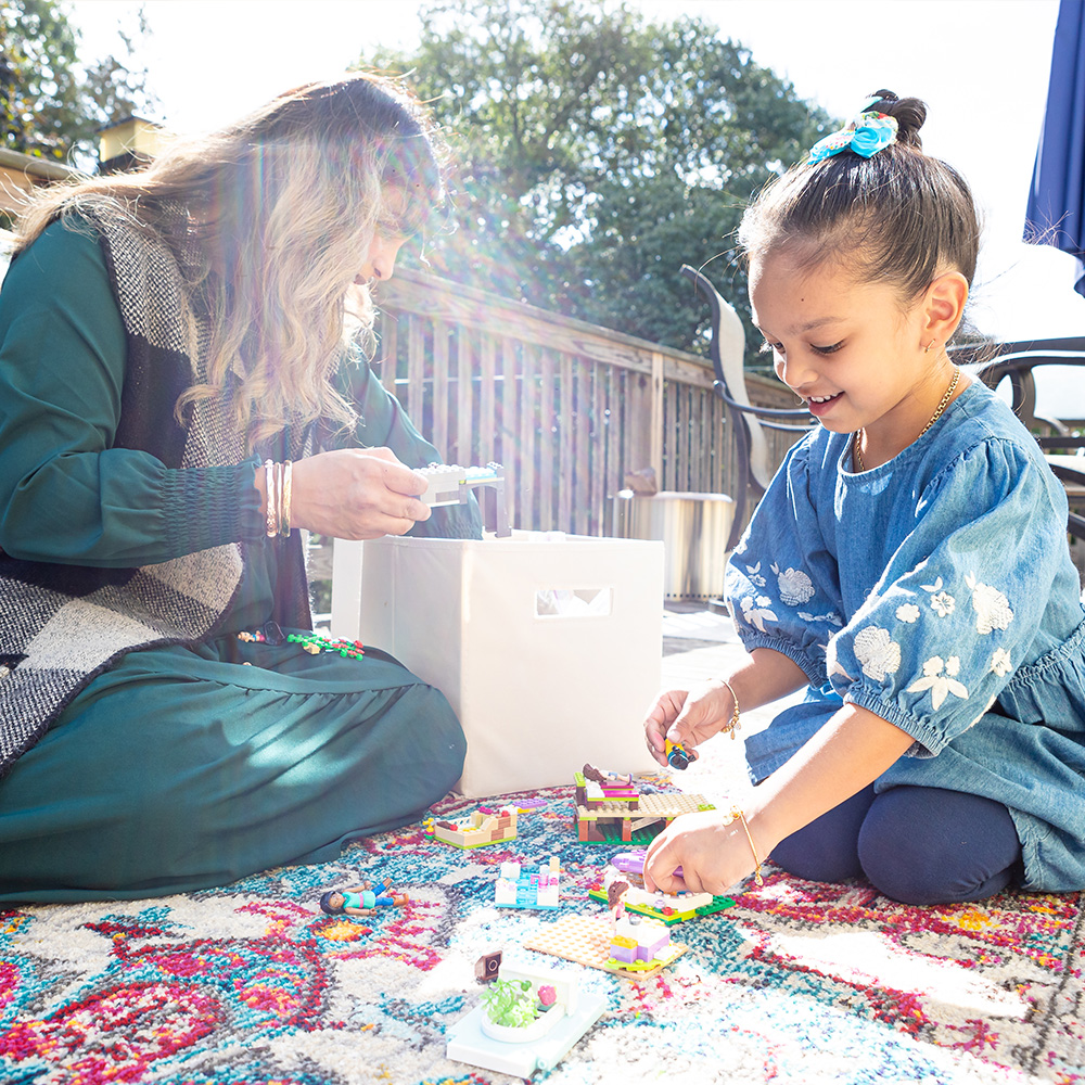 Researcher evaluating a young child playing outside on a mat.