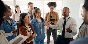 People wearing stethoscopes and taking notes, with a consultant teaching in a healthcare professional development setting.