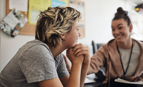 Women smiling and talking with a young person in a behavioral health setting.