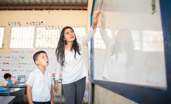 Teacher and student in a classroom, representing education workforce and systems.