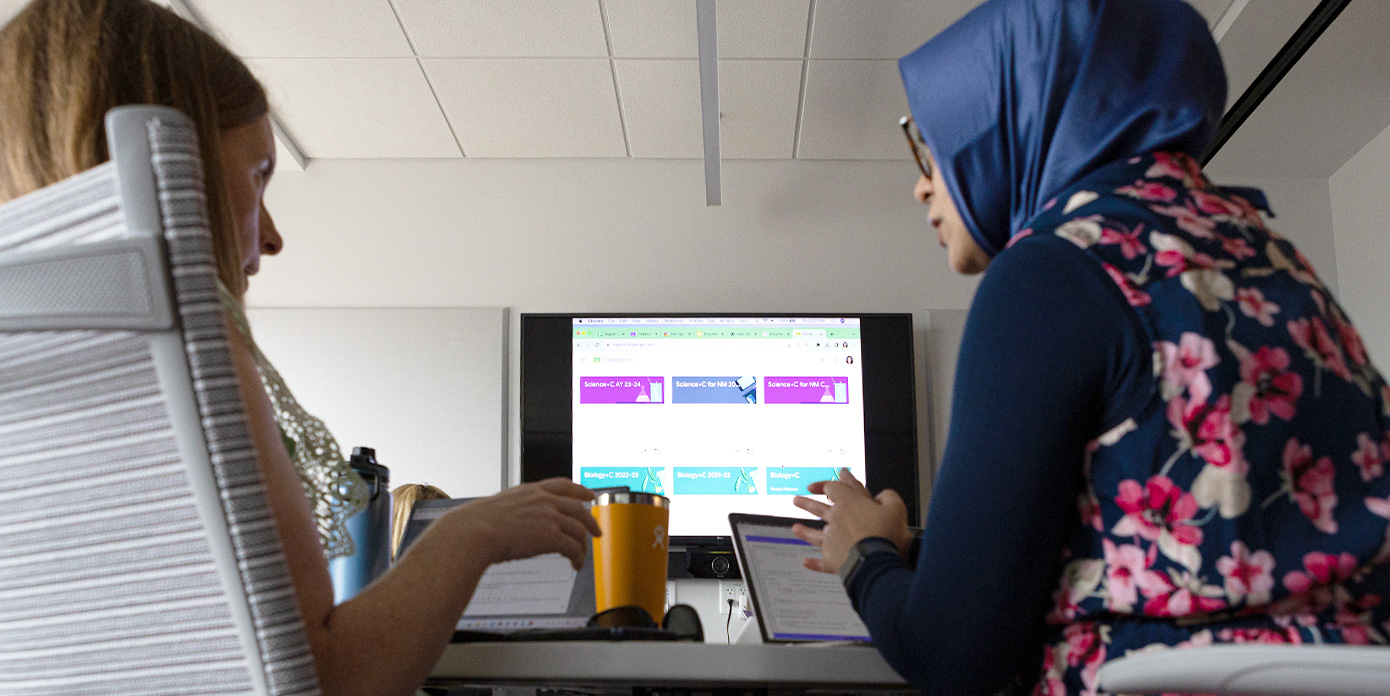Two people seated in front of a computer, working together.