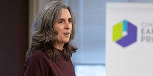 EDC employee speaking to a room and holding a stack of paper