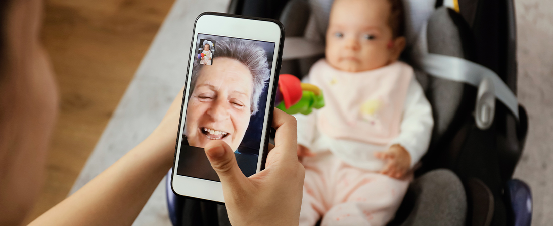 A photo of an older adult using FaceTime calling an infant in a rocking chair